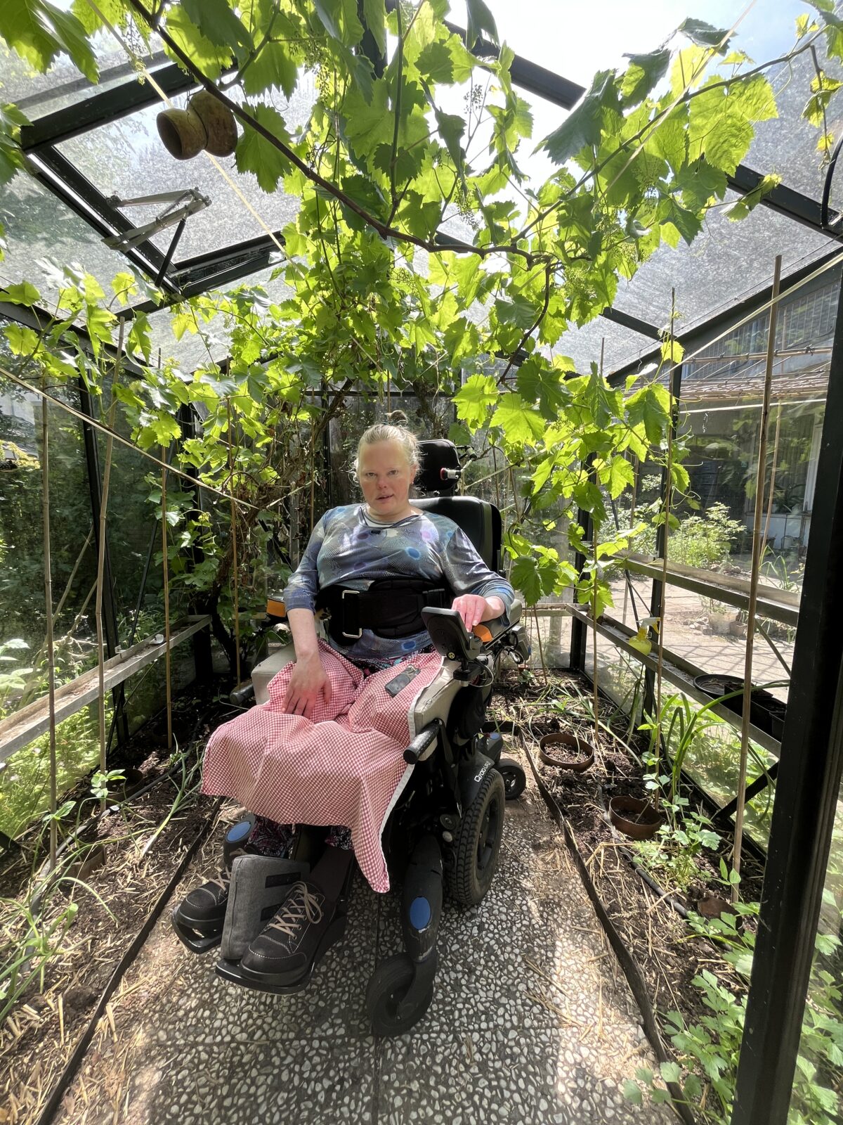 Gerda van Deelen in de plantenkas in haar tuin